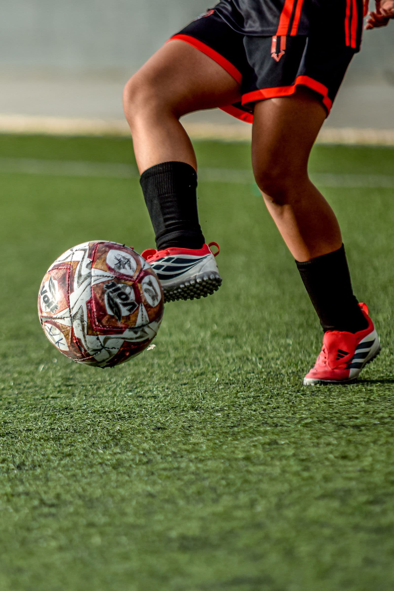Close-up of a player's feet controlling the ball on an artificial pitch